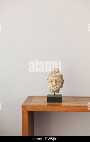 Tête de Bouddha sur ridelle devant un mur gris Banque D'Images