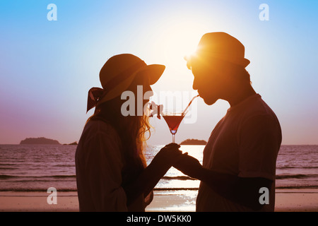 Partager le plaisir, couple drinking cocktail sur la plage Banque D'Images