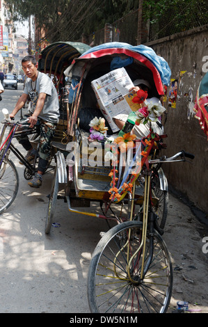 Un conducteur de pousse-pousse lire un journal à Katmandou au Népal Banque D'Images