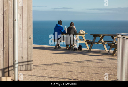 Couple assis à une table en plein air donnant sur la mer depuis le château de Durlston, Swanage, à l'île de Purbeck, Dorset, England, UK. Banque D'Images