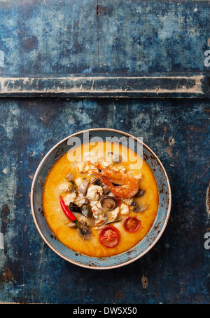 Soupe Thaï épicé Tom Yam au Lait de Coco, Piments et fruits de mer sur fond bleu Banque D'Images