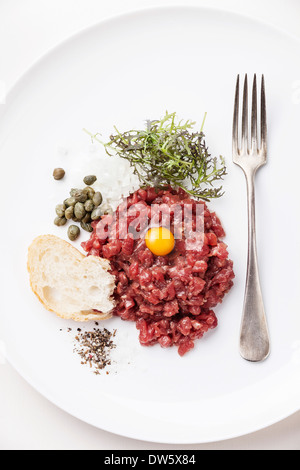 Tartare de boeuf aux câpres et oignons frais sur fond blanc Banque D'Images