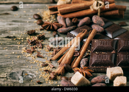 Chocolat noir avec des fèves de cacao, cannelle et anis sur fond de bois. Banque D'Images