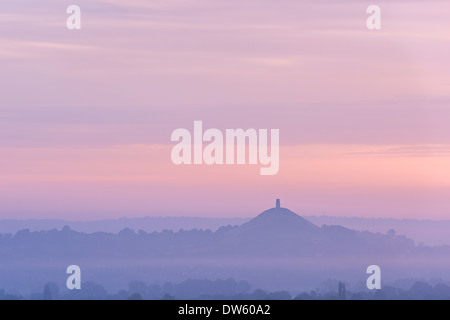 Glastonbury Tor rising entouré de brume à l'aube, Somerset, Angleterre. L'été (août) 2013. Banque D'Images