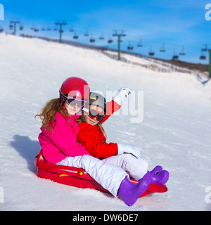 Kid in traîneau dans la neige avec des casques et lunettes Banque D'Images