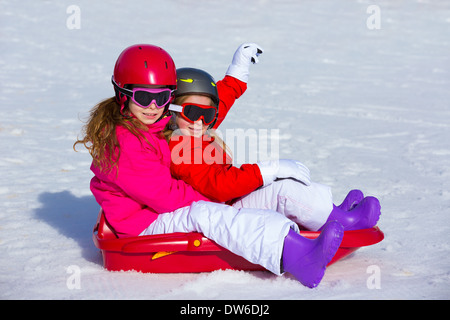 Kid in traîneau dans la neige avec des casques et lunettes Banque D'Images