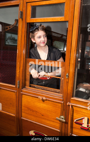 Une jeune femme en costume des années 1940 donne d'une fenêtre ouverte du transport ferroviaire Banque D'Images