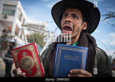 Le Caire, Égypte. 1er mars 2014. Un Égyptien pro-régime militaire partisan tenant un Coran et une Bible cris slogan devant des barbelés à l'extérieur de l'École de police où un procès de l'ancien président déchu Mohamed Morsi plus de chefs d'incitation à tuer des manifestants, l'ouverture est prévue au Caire, capitale de l'Égypte, le 1 mars 2014. Morsi et 14 autres prévenus sont accusés d'incitation à la violence et l'ordre de tuer des manifestants devant le palais présidentiel en décembre 2012. Source : Xinhua/Chaoyue Pan/Alamy Live News Banque D'Images