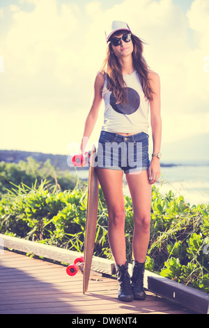 Belle fille hipster avec skate board portant des lunettes de soleil Banque D'Images