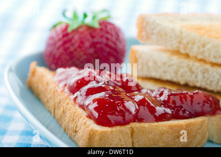 Tranches de pain grillé avec de la confiture de fraises rouges et de baies fraîches sur fond bleu vintage Banque D'Images