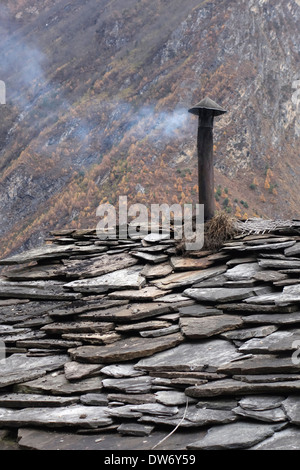 La fumée de bois sortant d'une cheminée sur une maison avec une toiture en ardoise dans la région du Manaslu au Népal. Banque D'Images