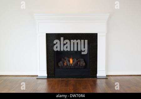 Photo horizontale d'un foyer au gaz naturel avec un manteau blanc et un sol en bois de cerisier Banque D'Images