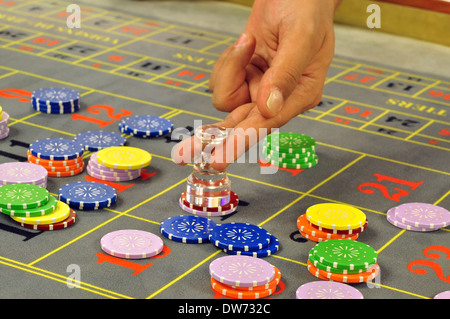 Image d'une roulette de casino modèle gris avec plein de jetons et le concessionnaire main tenant la dolly Banque D'Images