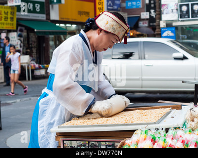 Une femme prépare des collations au gâteau de riz d'un marché à Insadong, Séoul. Banque D'Images