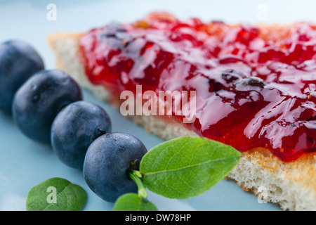 Tranches de pain grillé avec de la confiture de bleuets et de baies fraîches sur fond bleu vintage Banque D'Images