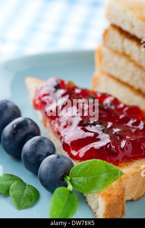 Tranches de pain grillé avec de la confiture de bleuets et de baies fraîches sur fond bleu vintage Banque D'Images