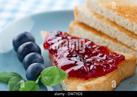 Tranches de pain grillé avec de la confiture de bleuets et de baies fraîches sur fond bleu vintage Banque D'Images