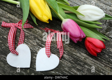 Deux coeurs le Jour de Valentines avec tulipes de couleur sur fond de bois Banque D'Images