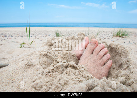 Pieds enfouis dans le sable avec les orteils à découvert sur une plage Banque D'Images