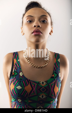 Portrait of young woman looking at camera avec une attitude. Beau modèle féminin posant sur fond gris Banque D'Images