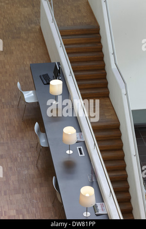 Bibliothèque publique de Genk, Genk, Belgique. Architecte : Claude Vasconi, 2008. Bureau avec lampes blanches et plancher en bois au premier étage, vu Banque D'Images