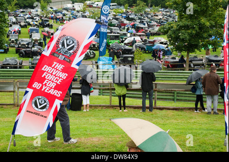 Les spectateurs à l'abri de la pluie sous des parasols sur le csecc vitesse prescott hill climb, Gloucestershire, Angleterre, Royaume-Uni. Banque D'Images