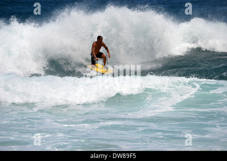 Bodyboarder sur son genou le surf une vague sur une plage de sable, à l'Est Oahu, Hawaii, USA Banque D'Images