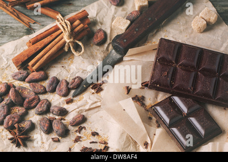 Vue de dessus sur le chocolat noir avec de vieux couteau, fèves de cacao, de cannelle et anis sur papier froissé. Banque D'Images