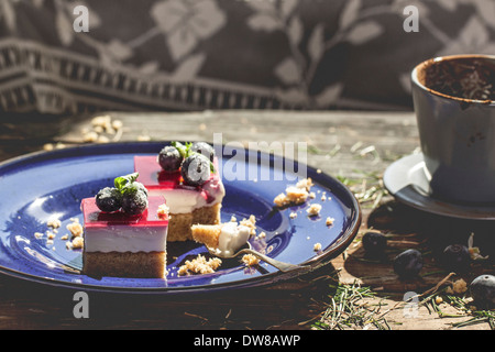 Dessert sur assiette en céramique bleue avec du café sur table en bois avec de l'herbe Banque D'Images