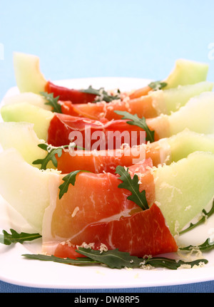 Melon mûr avec du jambon, fromage parmesan sur plaque blanche, soft focus Banque D'Images