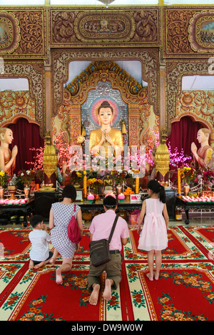 Les membres de la famille de prier à l'intérieur de l'Dhammikarama, un temple bouddhiste birman à Penang en Malaisie. Banque D'Images