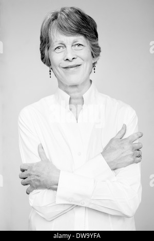 Le noir et blanc studio portrait of senior woman with arms folded Banque D'Images
