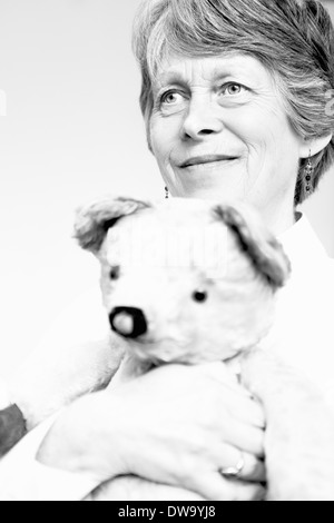 Le noir et blanc studio portrait of senior woman holding teddy bear Banque D'Images