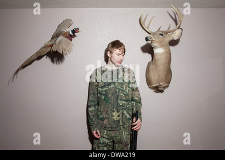 Home portrait of teenage boy holding shotgun Banque D'Images