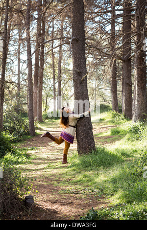 Young woman hugging tree trunk in forest Banque D'Images