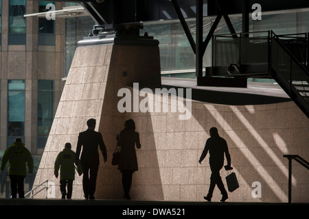 Silhouettes de Londoniens de marcher dans les bureaux d'entreprise Broadgate développement dans la ville de Londres. Une personne est porteuse d'un panier et d'autres font leur chemin dans une zone de surface sous la grande architecture en acier avec la toile de la Broadgate le développement au sein de l'ancienne frontière de la capitale le Square Mile, c'est quartier financier fondée par les Romains en l'an43. Banque D'Images