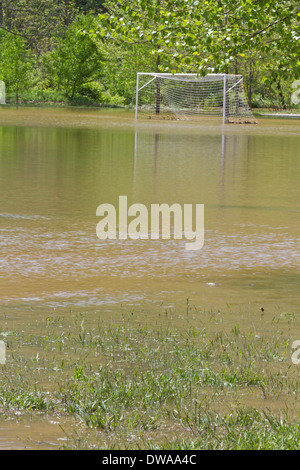 Un but de soccer se trouve dans l'eau dans un champ inondé par une rivière à proximité Banque D'Images