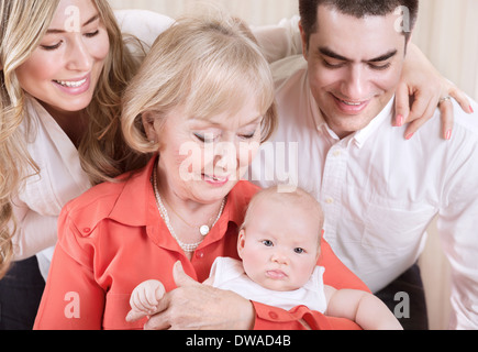 Portrait de famille heureuse, joyeuse mère et père debout près de Granny tenue bébé nouveau-né sur les mains, l'amour et l'unité Banque D'Images