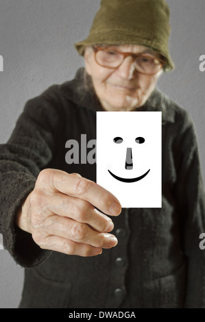 Femme âgée en tenant la carte avec des imprimés professionnels émoticône. Selective focus sur la carte et les doigts. Banque D'Images