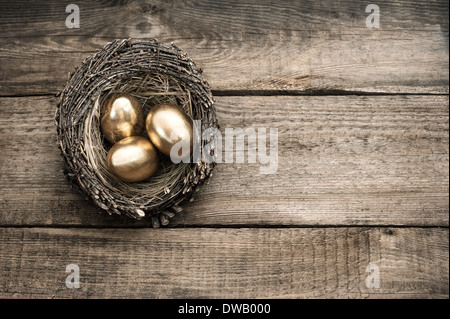 Oeufs de Pâques en or oiseaux nichent sur fond de bois vintage Banque D'Images