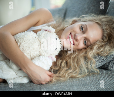 Portrait de jeune femme avec ours lying on sofa Banque D'Images