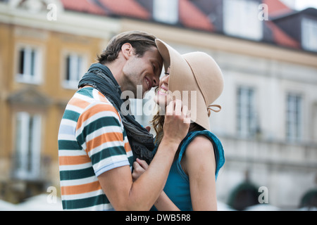 Jeune homme romantique femme baiser contre les bâtiments Banque D'Images