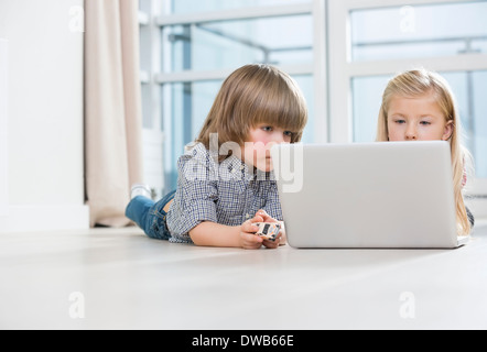 Garçon et fille à l'aide de l'ordinateur portable sur marbre à la maison Banque D'Images