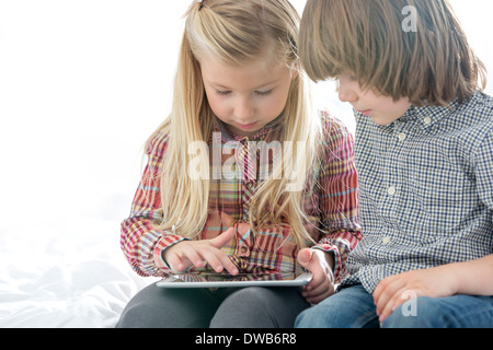 Frère et soeur à l'aide de Tablet PC dans la chambre Banque D'Images