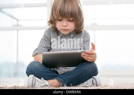 Toute la longueur de boy using digital tablet in living room Banque D'Images