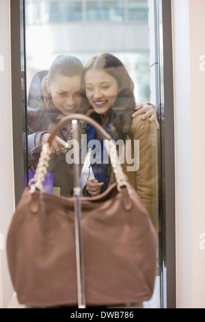 Happy female friends looking at sac à main par la fenêtre d'affichage Banque D'Images