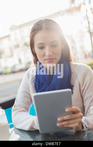 Woman using tablet PC at sidewalk cafe Banque D'Images