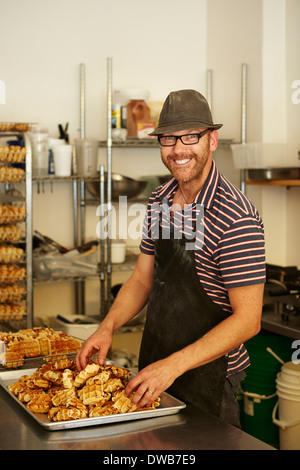 Homme Baker avec plateau de gaufres dans une boulangerie Banque D'Images