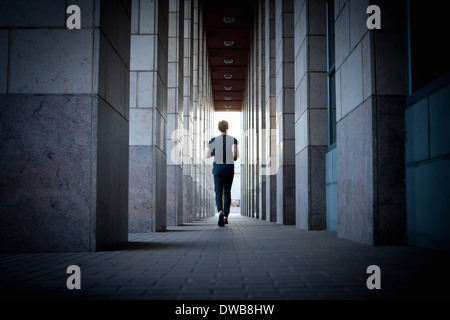 Jeune homme qui courait le long des trottoirs urbains Banque D'Images