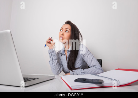 Thoughtful businesswoman sitting at office desk Banque D'Images